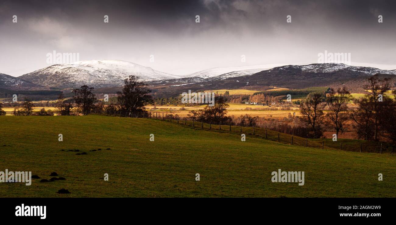 Una raffica di luce del sole cade sulla valle di Strathspey e le montagne coperte di neve del Cairngorms a Kingussie nelle Highlands della Scozia. Foto Stock