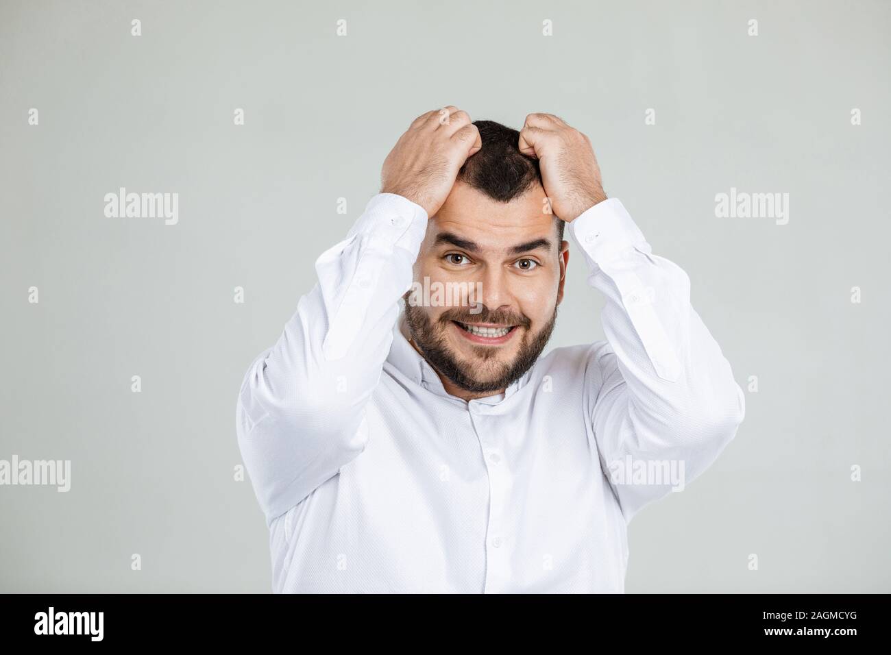 Uomo Barbuto mantiene la mano sulla testa su sfondo grigio. l uomo dimentica qualcosa Foto Stock