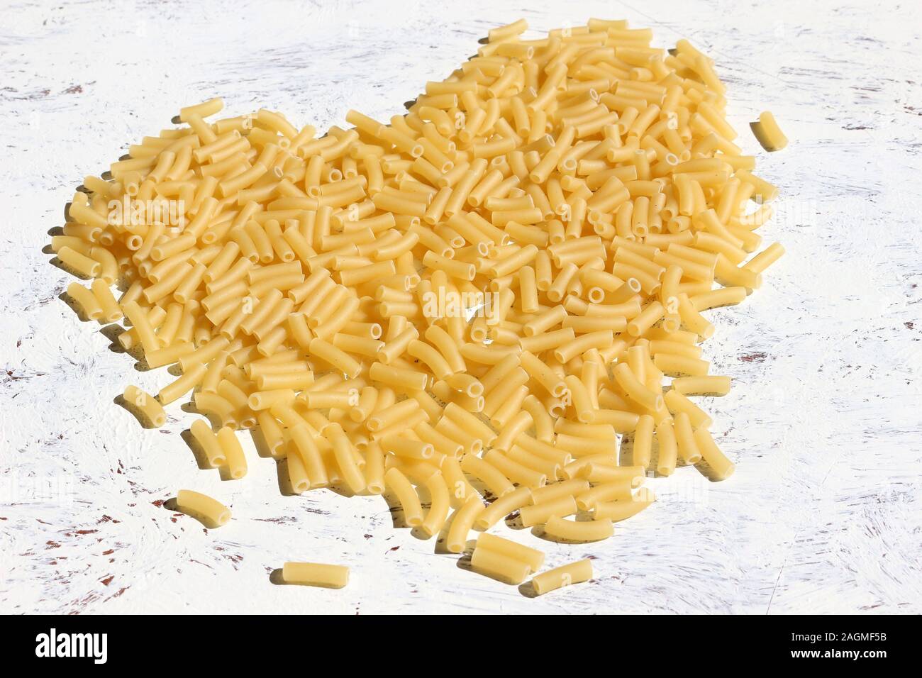 Pasta secca dello sfondo. Paste alimentari non cotte di pasta a forma di cuore su uno sfondo bianco Foto Stock