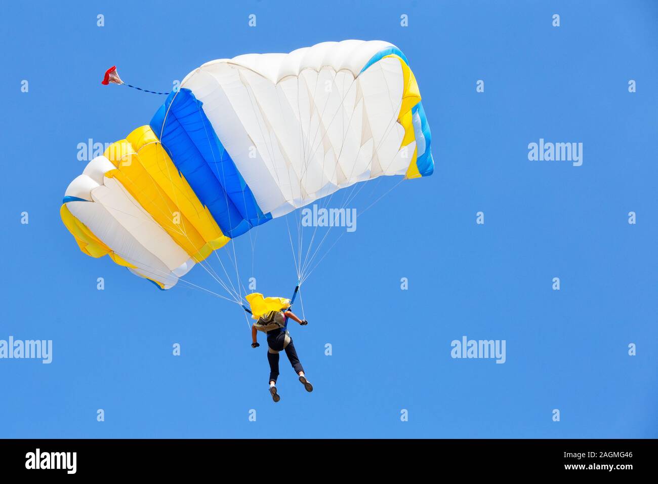 Paracadutista sotto la cupola di colore bianco di un paracadute nel cielo blu Foto Stock