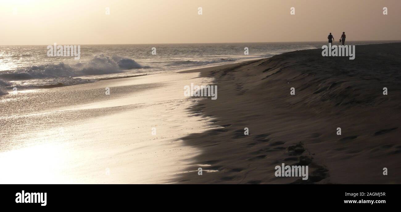 Un paio di godere di un tramonto a piedi su di una spiaggia appartata in Capo Verde Foto Stock