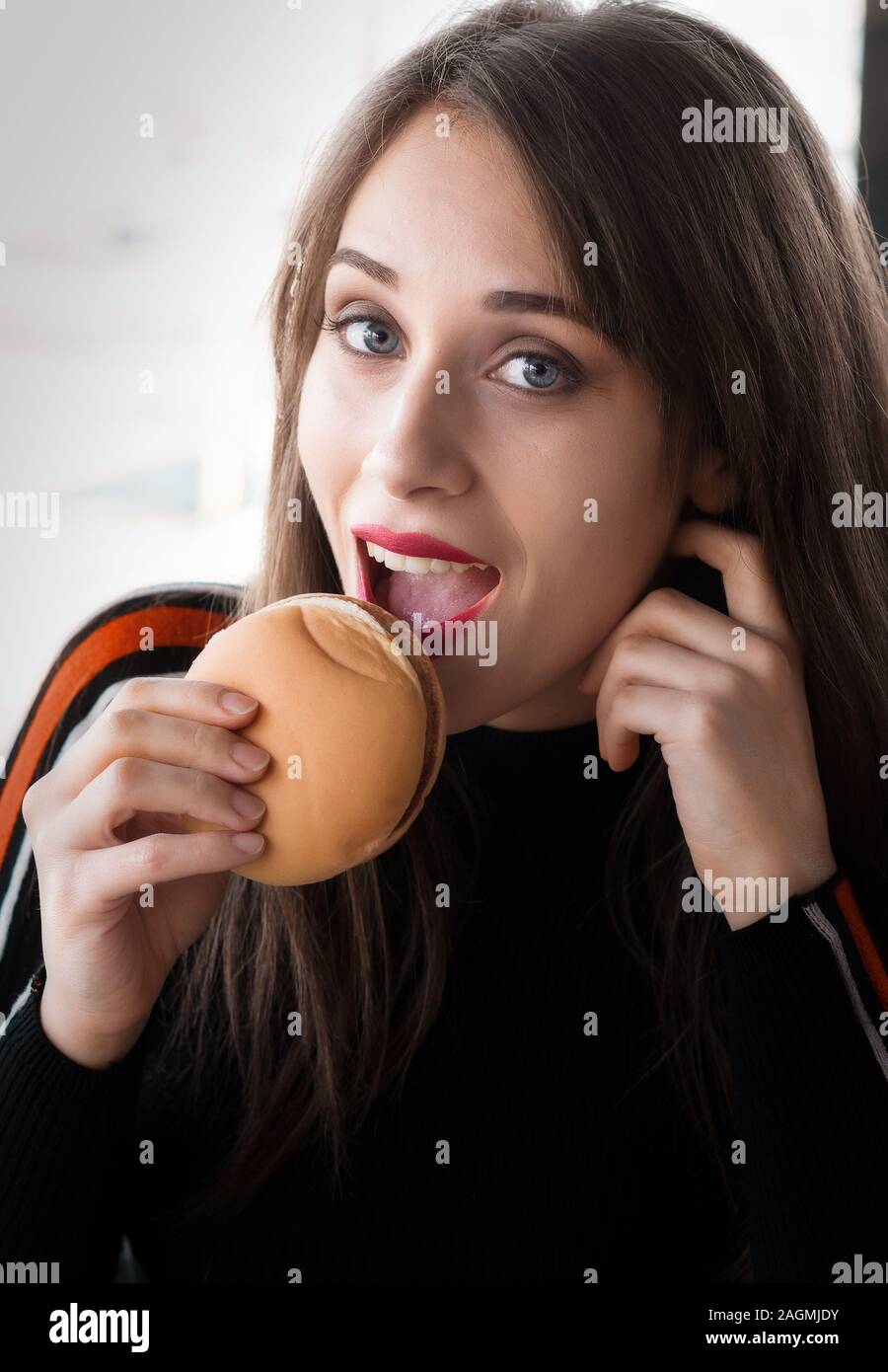 Ragazza in un ristorante fast food mentre mangiare un hamburger Foto Stock
