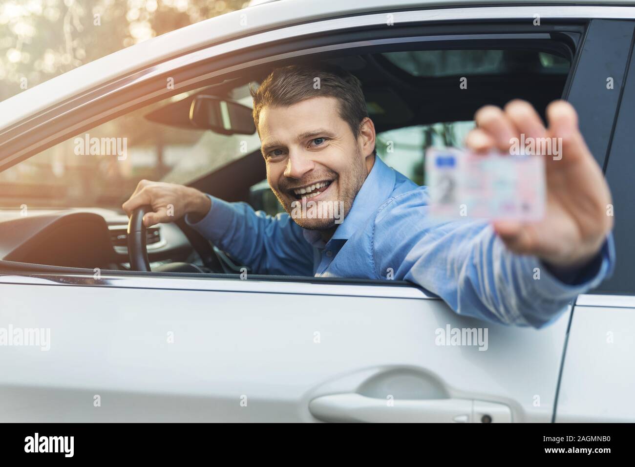 Uomo seduto in macchina e mostrando la sua licenza di pilota al di fuori della finestra di auto Foto Stock
