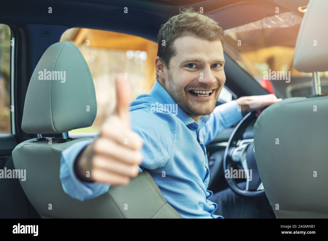 Uomo seduto dentro la macchina e mostrando il pollice fino gesto Foto Stock