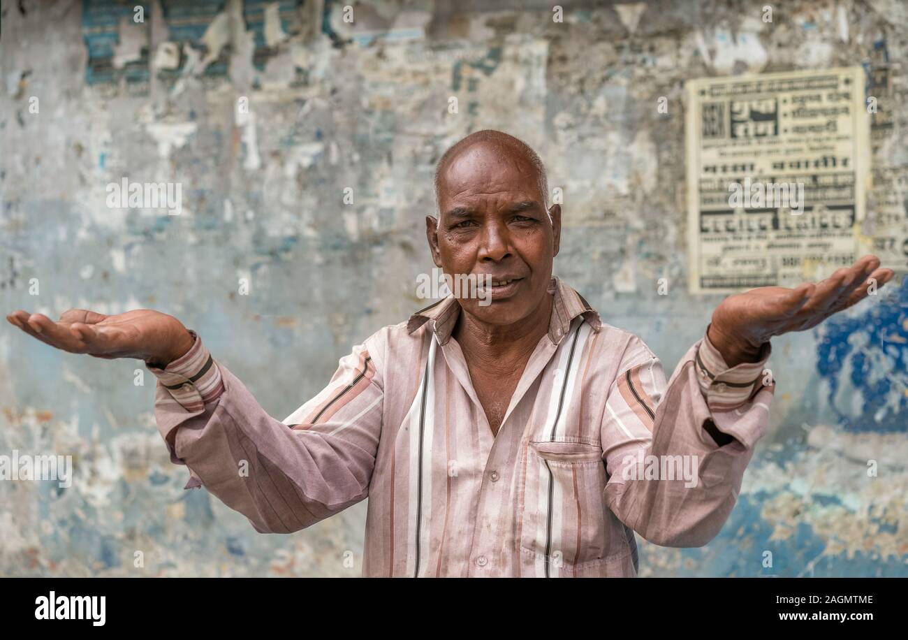 Ritratto di uomo che vive sulle strade rende interrogatorio gesto contro la parete sfigurata in Udaipur, Rajasthan, India. Foto Stock