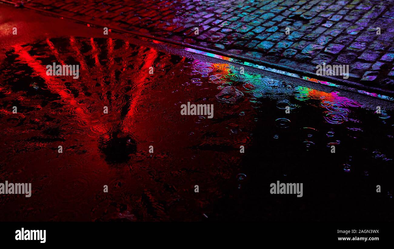 Ruota panoramica Ferris si riflette in una pozza di rosso a una fiera del divertimento di notte Foto Stock