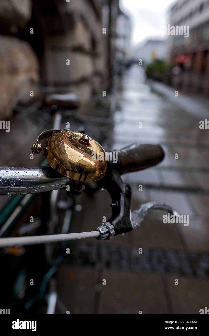 Close up della campana in ottone di una bicicletta parcheggiata in una strada a Monaco di Baviera in un giorno di pioggia Foto Stock