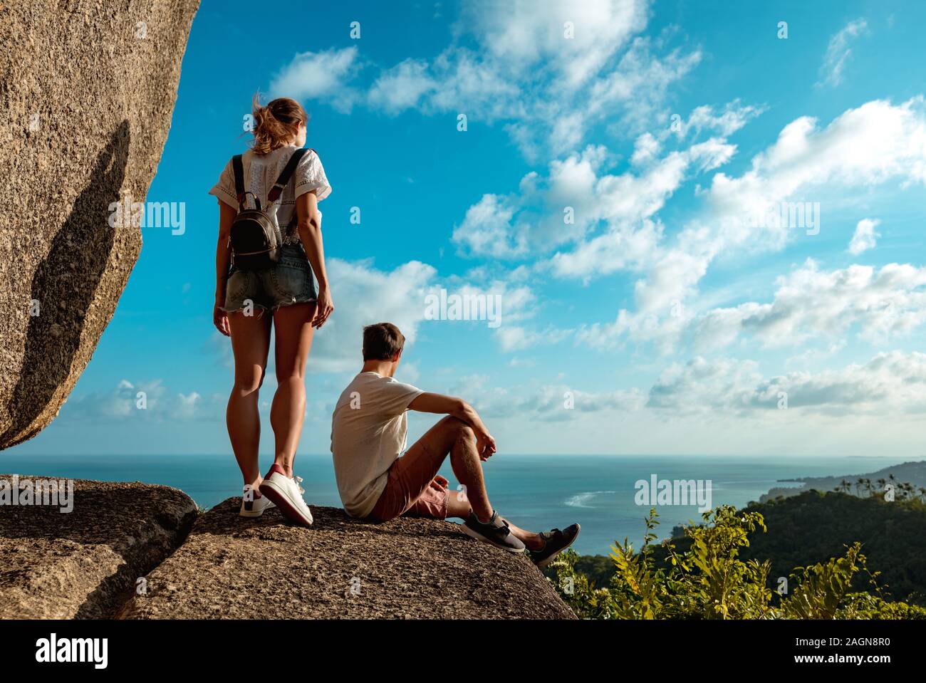 Bella coppia di escursionisti sorge sulla grande roccia di montagna e guardando il mare e la giungla Foto Stock