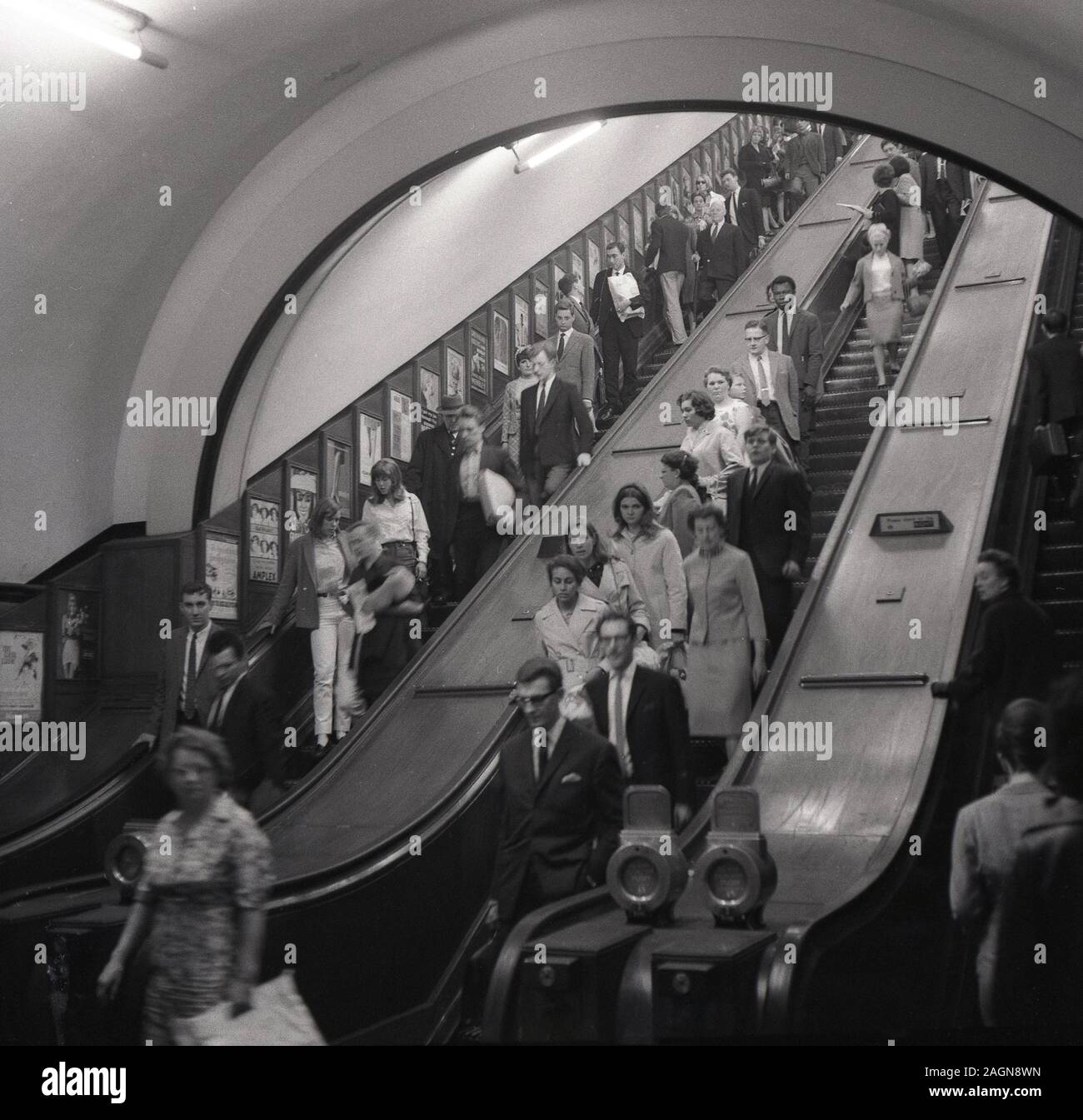 Anni sessanta, storico, persone scendendo le scale mobili della metropolitana di Londra, Londra, Inghilterra, Regno Unito. Foto Stock