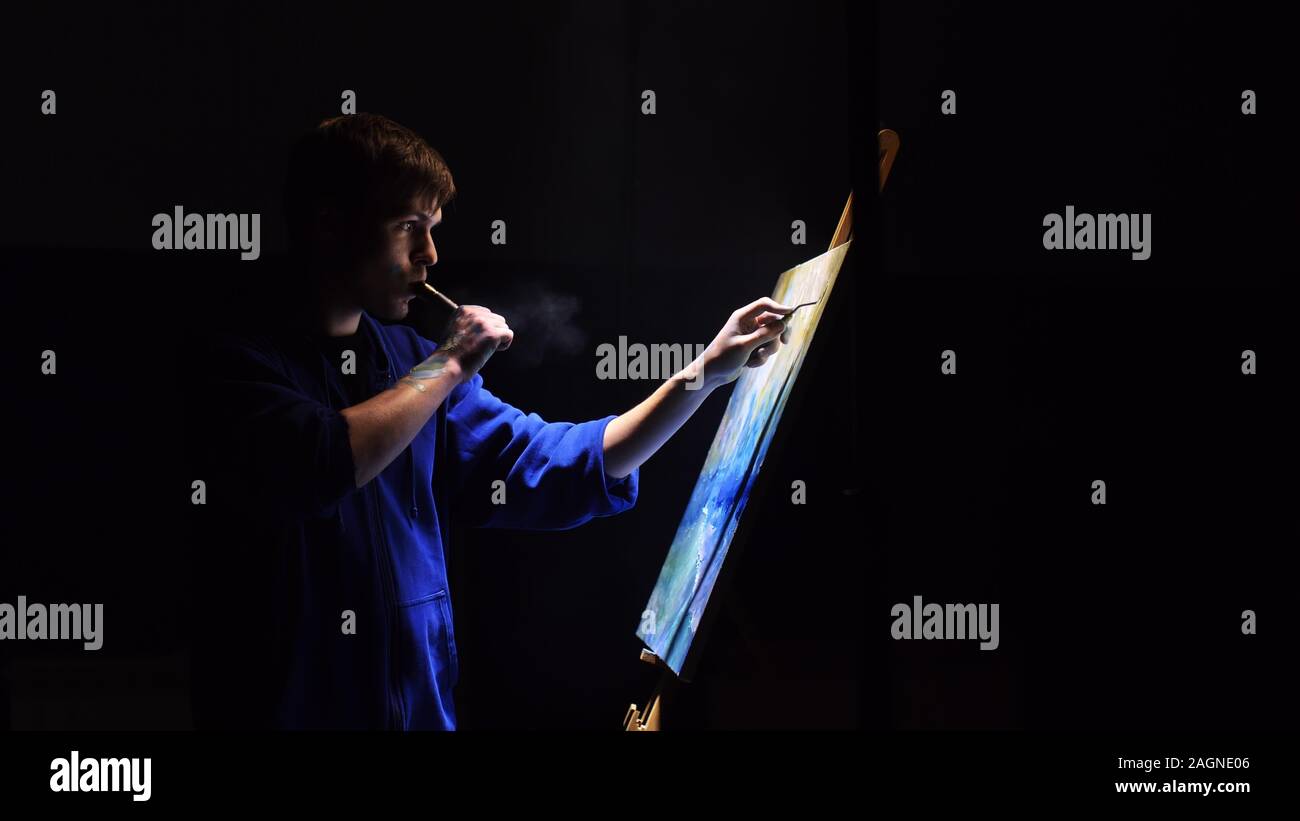 Artista copista paint seascape con nave in oceano. Fumo Vaper vape e-sigaretta. Artigiano arredatore disegnare come barca vela sul mare blu con colori acrilici. Foto Stock