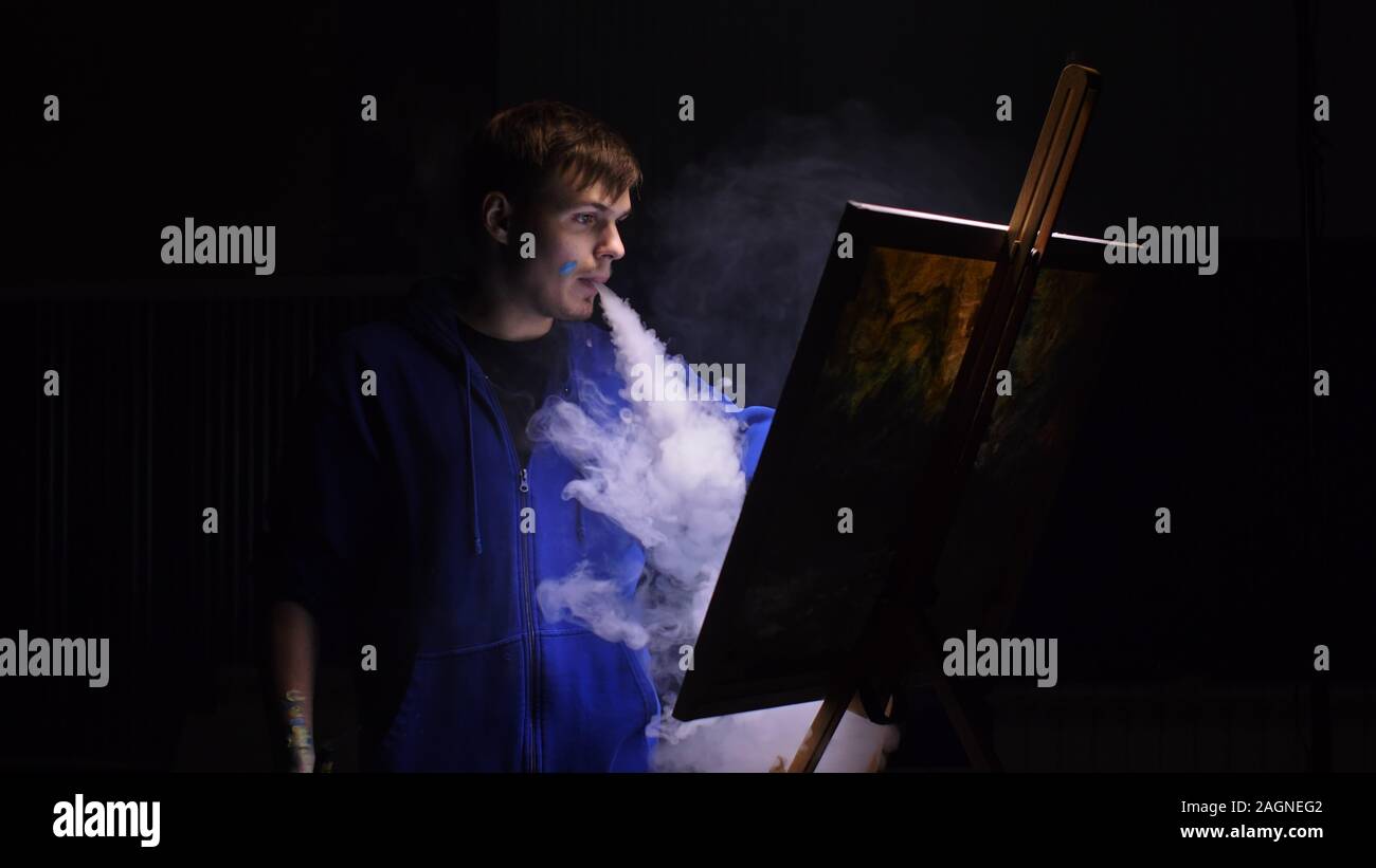 Artista copista paint seascape con nave in oceano. Fumo Vaper vape e-sigaretta. Artigiano arredatore disegnare come barca vela sul mare blu con colori acrilici. Foto Stock