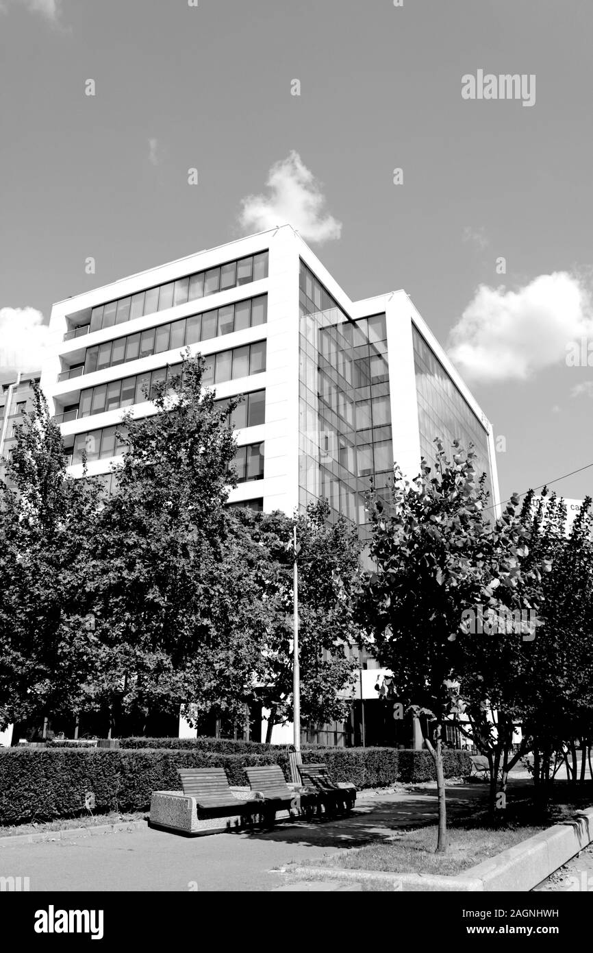Città ufficio moderno edificio con alberi e panchine. Foto in bianco e nero o di fotografia Foto Stock