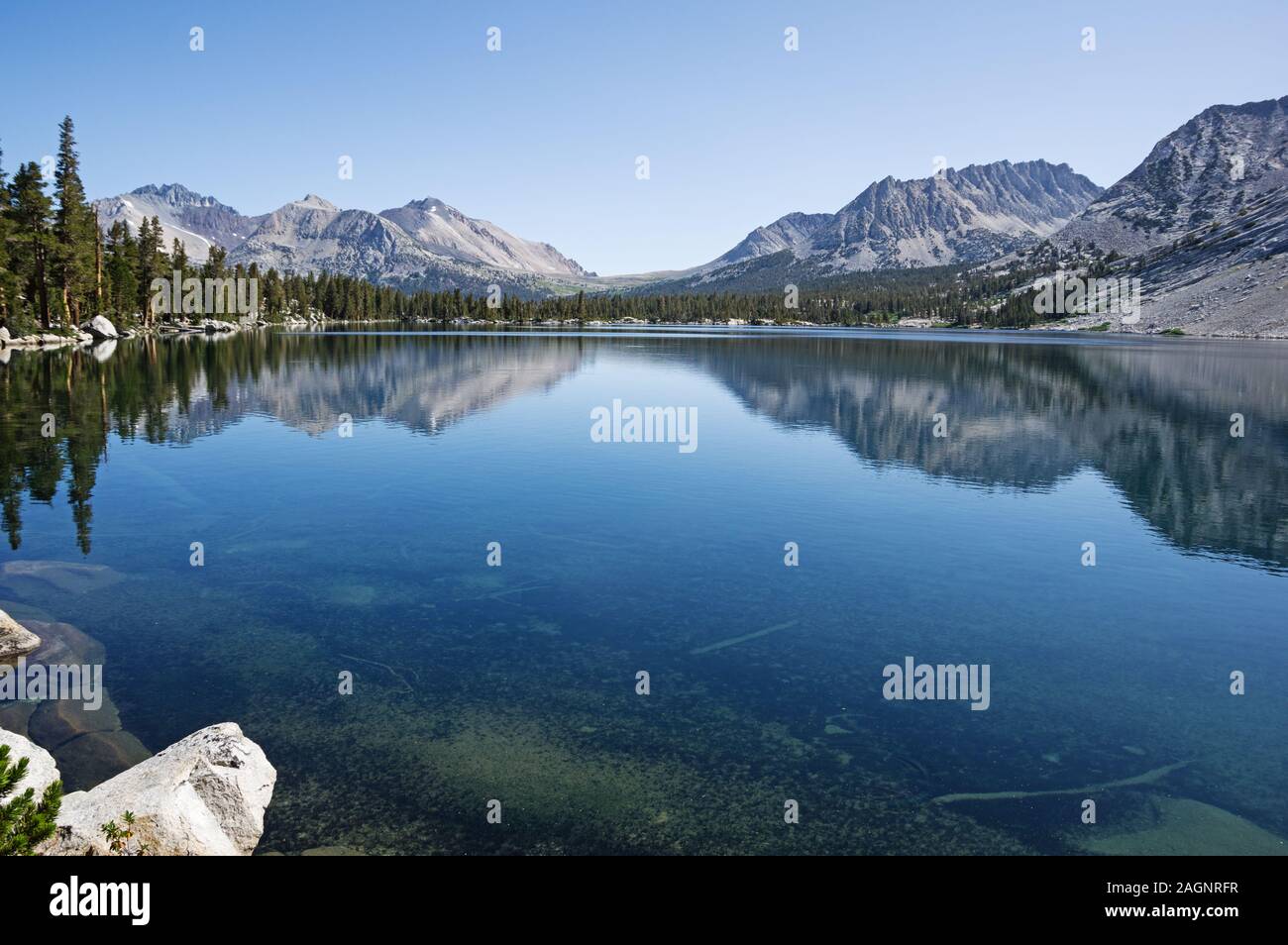 La riflessione di montagne in blu chiaro lago da banco in Kings Canyon National Park Foto Stock