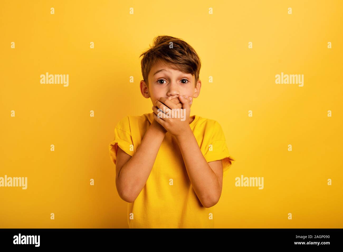 Bambino sorpreso vuole parlare. Stupiti e si chiedeva di espressione. Sfondo giallo Foto Stock