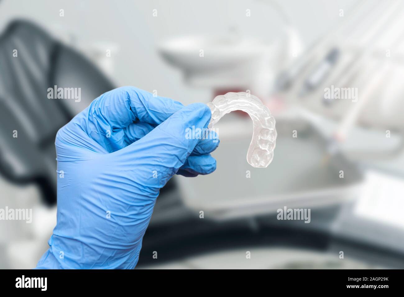 La mano nel vano di contenimento allineatore invisibile, dentista sedia in background. Ortodonzia, cure dentarie concept Foto Stock