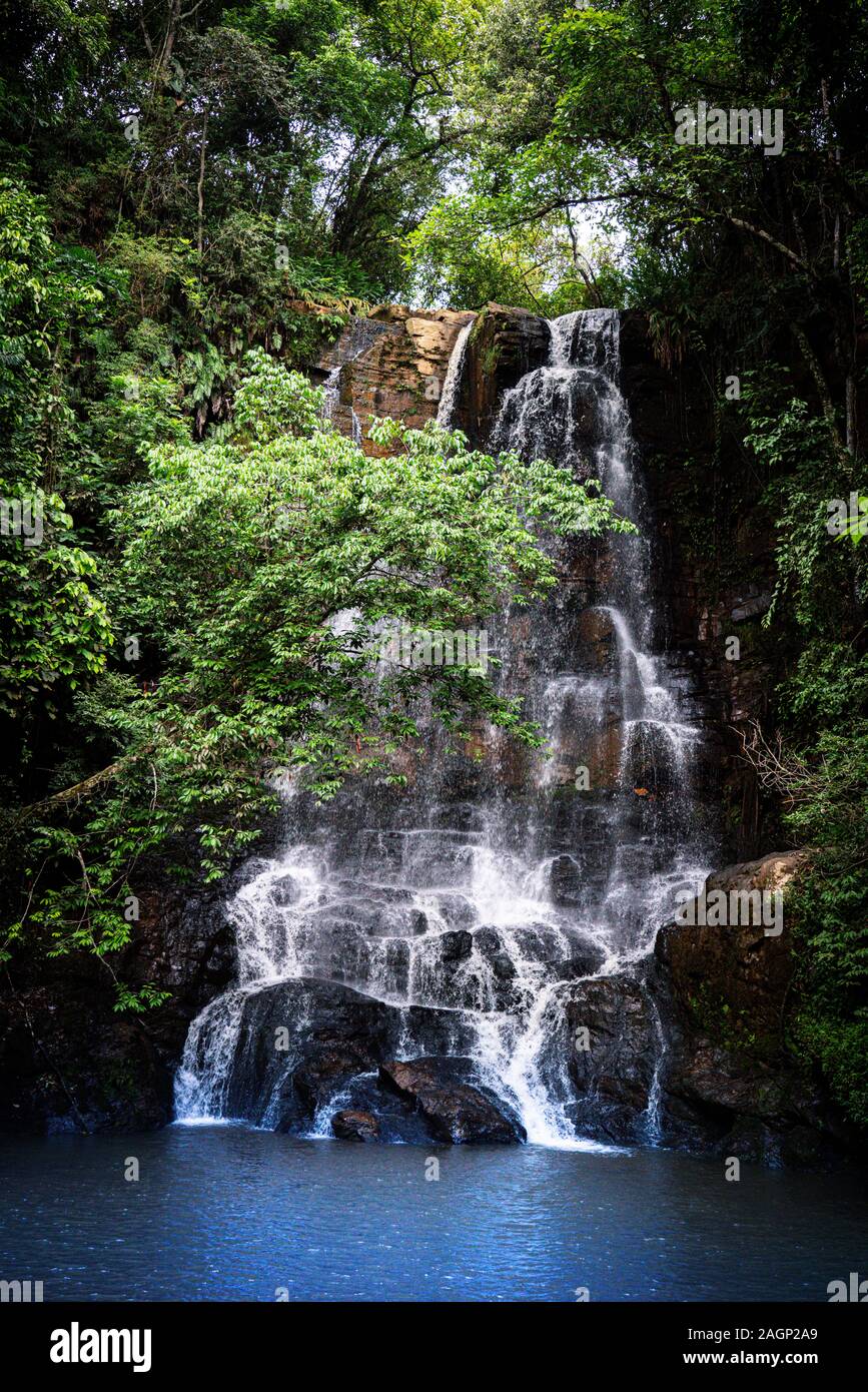 Bella cascata attraverso la vegetazione verde con rocce e un piccolo lago in Brasile Foto Stock
