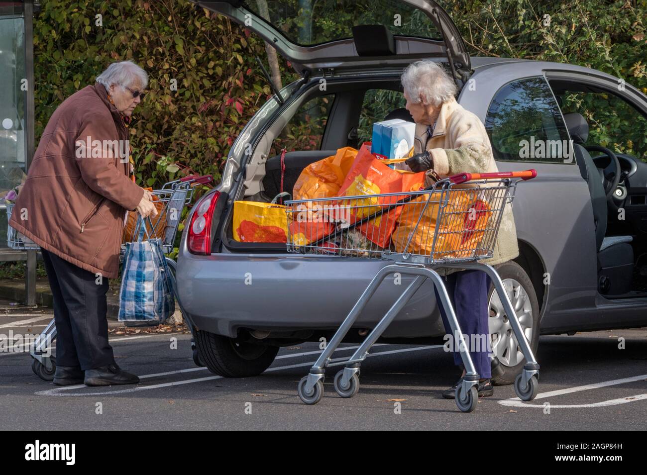 Donne anziane che scaricano lo shopping nella loro auto presso un parcheggio supermercato, Inghilterra, Regno Unito Foto Stock