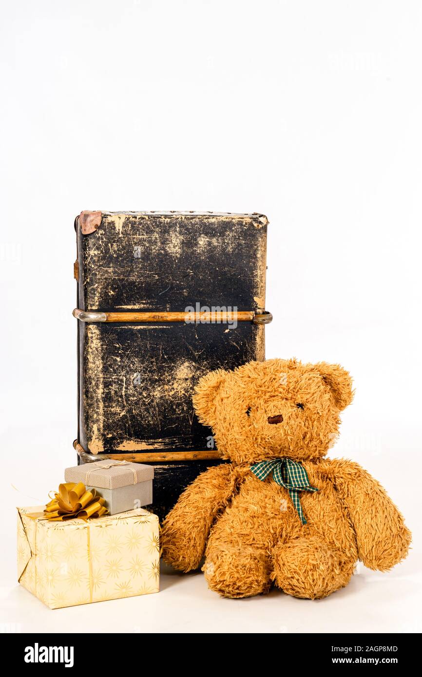 Brown simpatico orsacchiotto verde con nastro a scacchi seduta vicino vintage valigetta in pelle. Accanto a loro sono confezioni regalo. Con spazio per il testo. Foto Stock