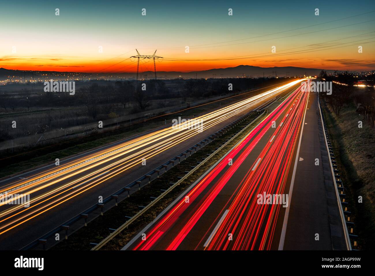 Auto sentieri di luce su una autostrada dritto al tramonto. Di notte i percorsi di traffico, motion blur, Night city road con traffico moto faro. Foto Stock