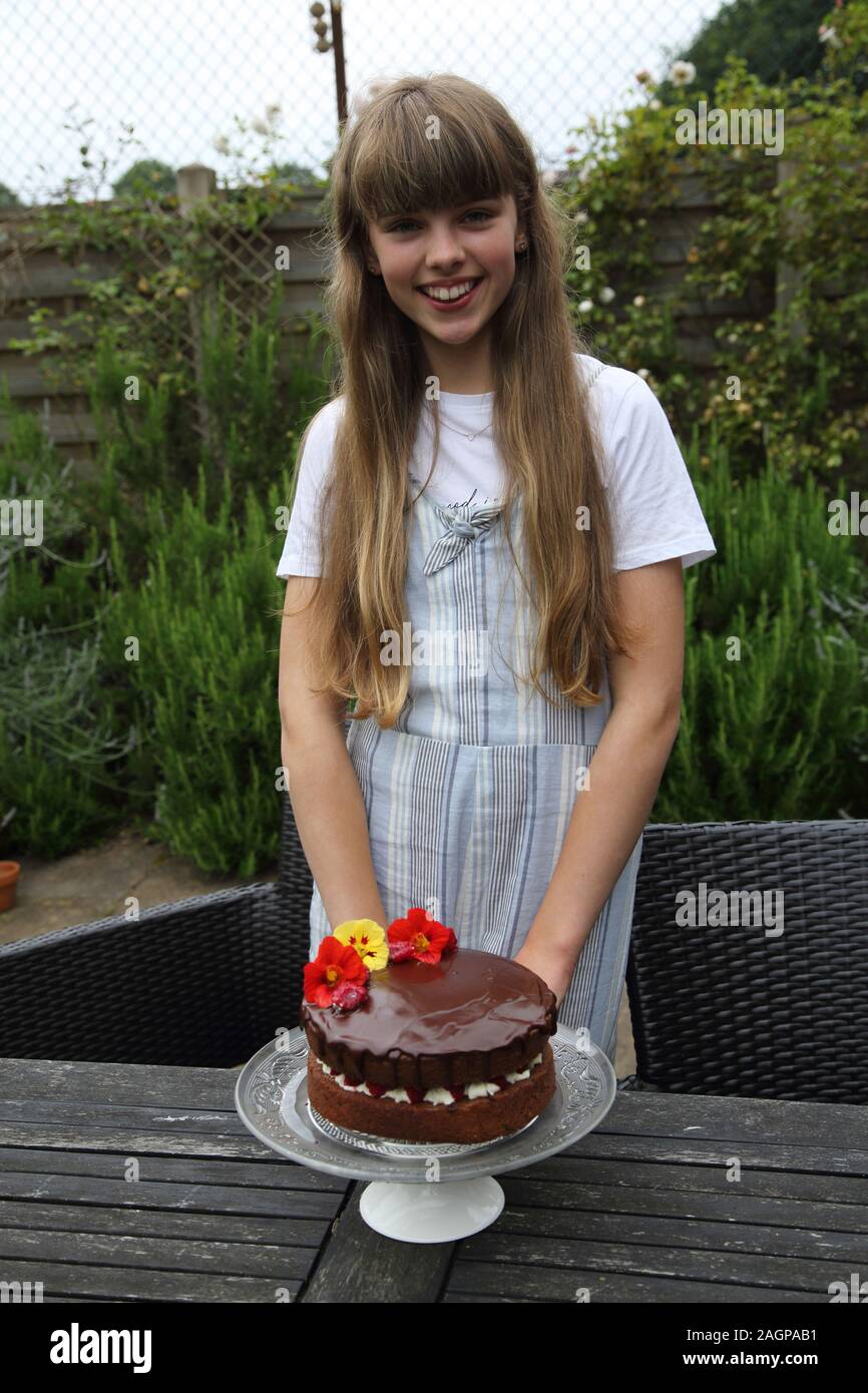Tredici anni di ragazza con il suo cioccolato artigianale Pan di Spagna Birmingham Inghilterra Foto Stock
