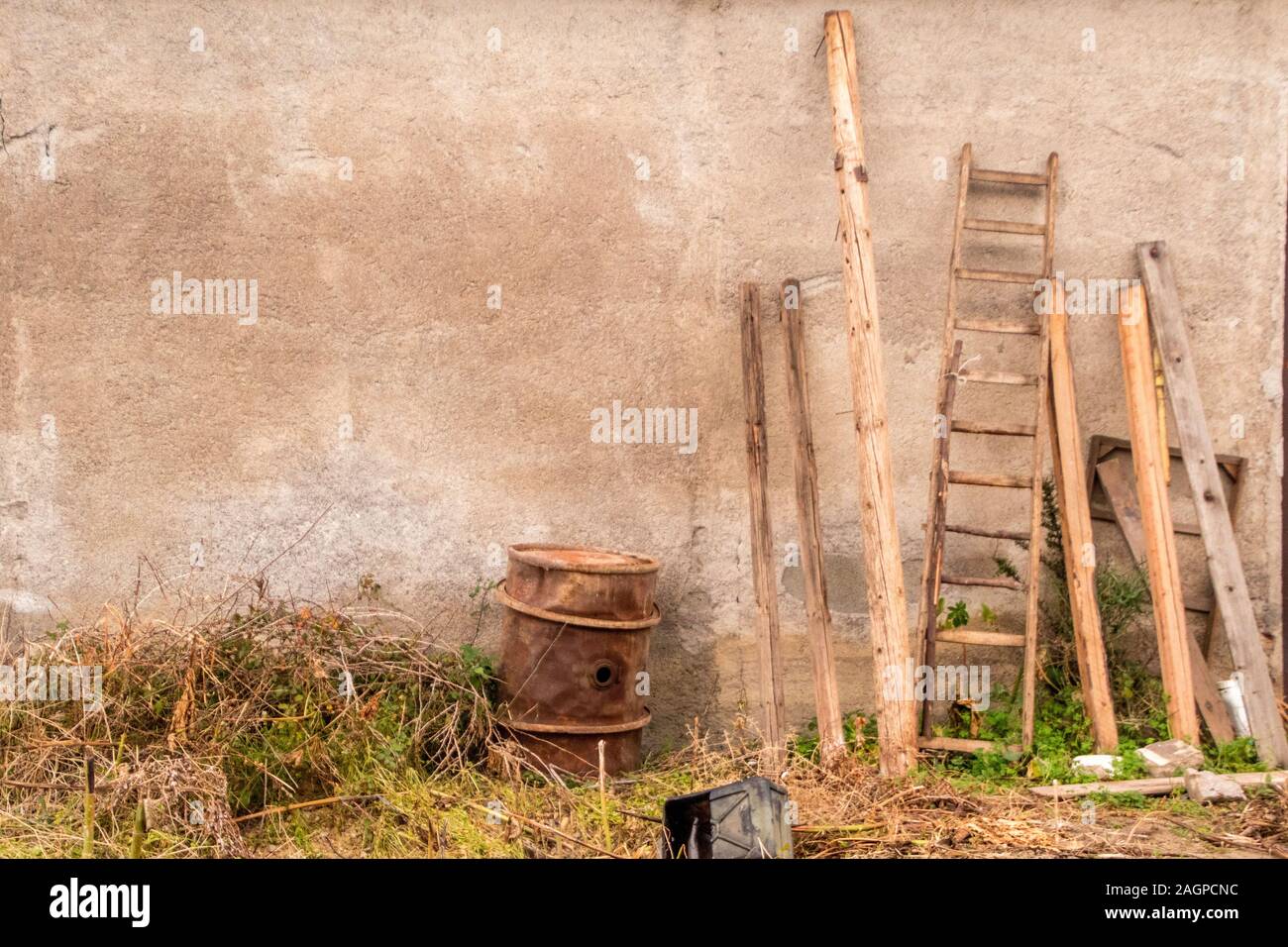 Varie capannone di fattoria di strumenti e apparecchiature poggiare contro una vecchia fattoria capannone della parete edilizia. Foto Stock