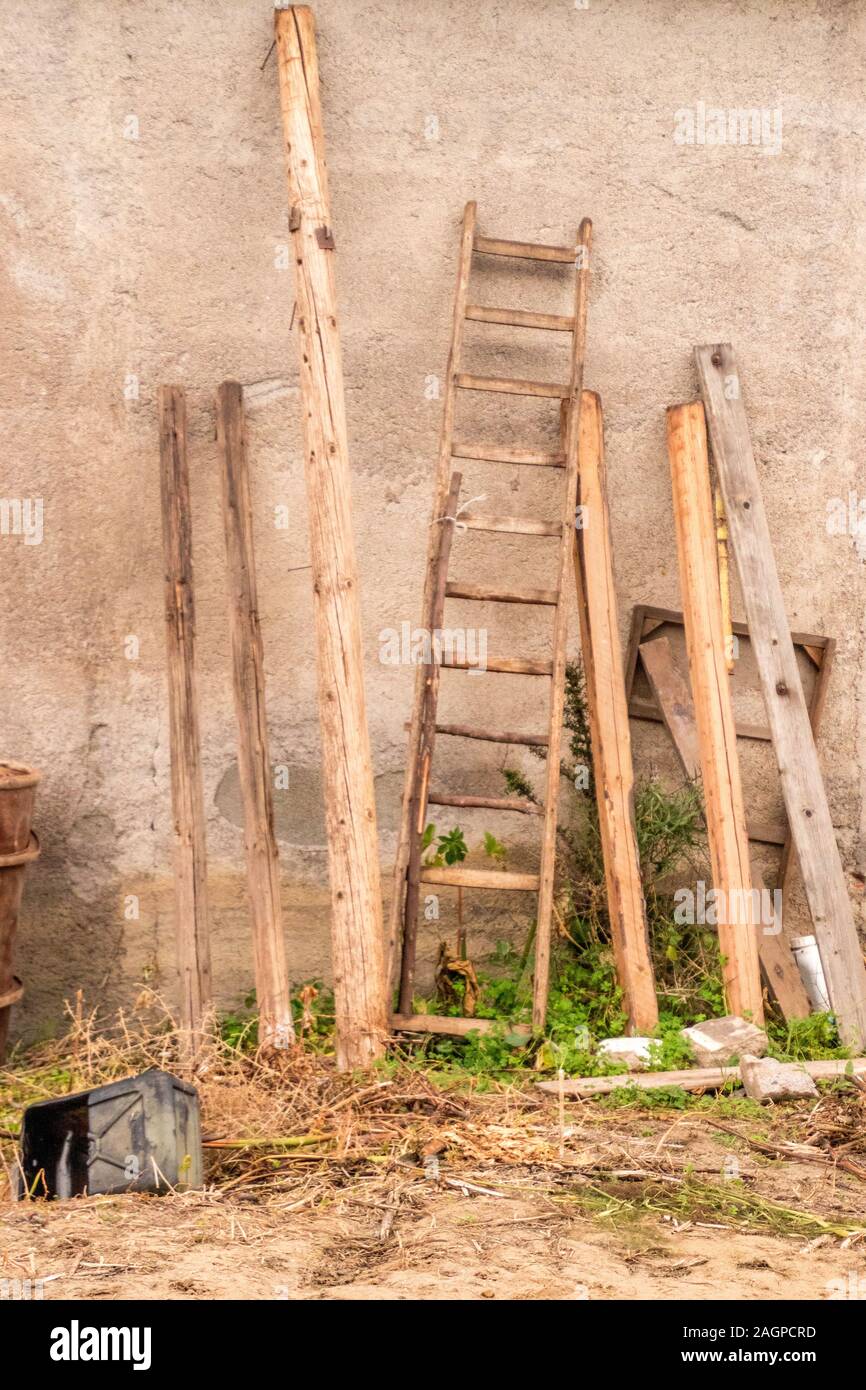Varie capannone di fattoria di strumenti e apparecchiature poggiare contro una vecchia fattoria capannone della parete edilizia. Foto Stock