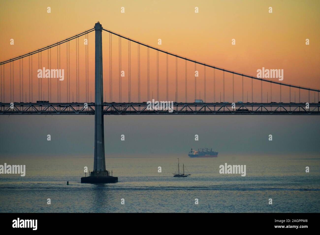 Ponte della Baia di San Francisco al tramonto con schooner e freighter nell'alloggiamento. Foto Stock