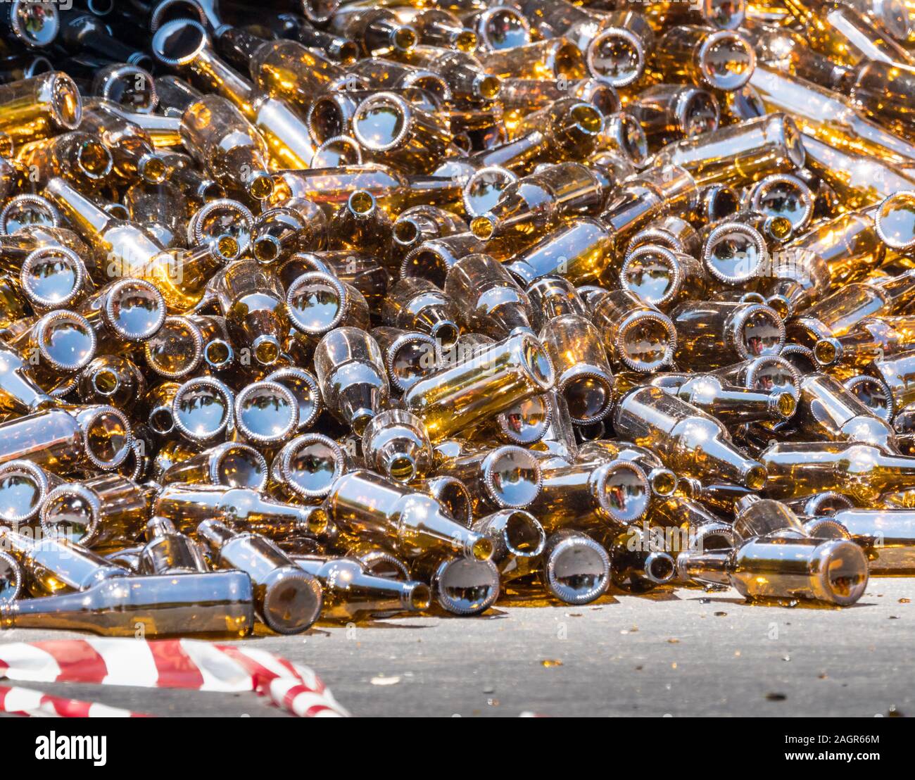 Heap carico o vuoti di bottiglie in vetro marrone giacenti in strada alla scena di un incidente con frammenti sparsi intorno Foto Stock