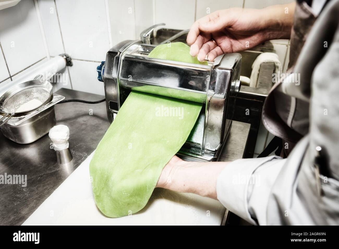 Lo chef è rendere sottile pasta con speciale macchina, tonica immagine Foto Stock