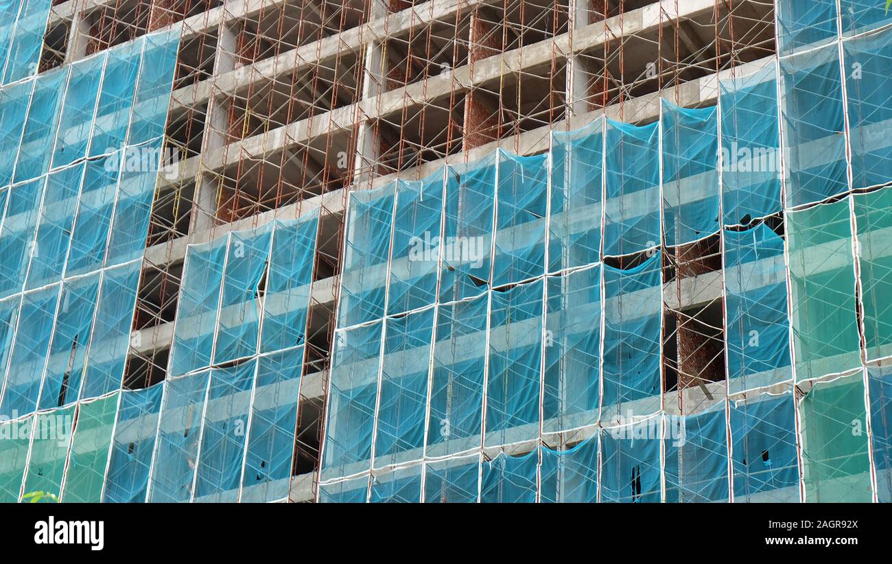 Alto edificio in costruzione, con struttura in metallo e rack di rete di sicurezza che copre l'esterno. Foto Stock