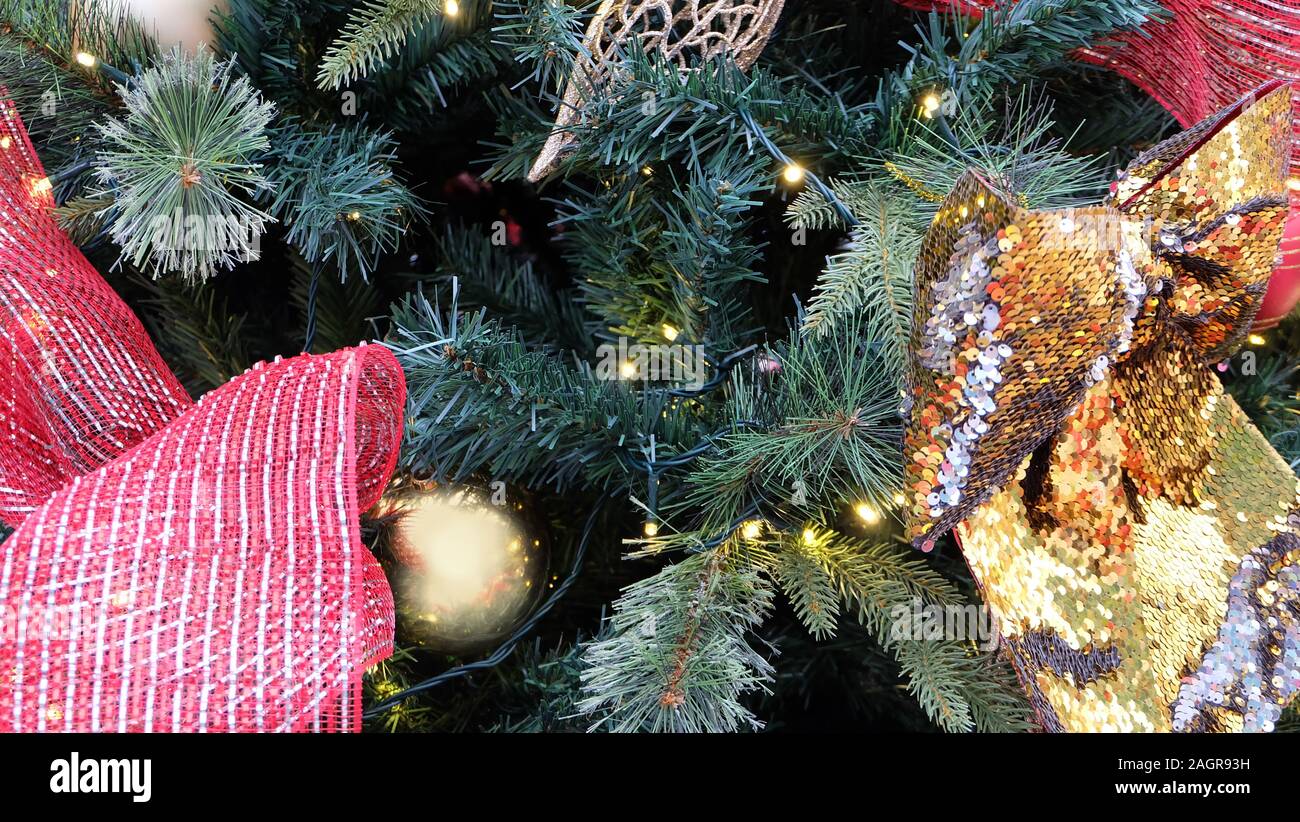 Primo piano di albero di Natale con luci, nastri e decorazioni. Foto Stock
