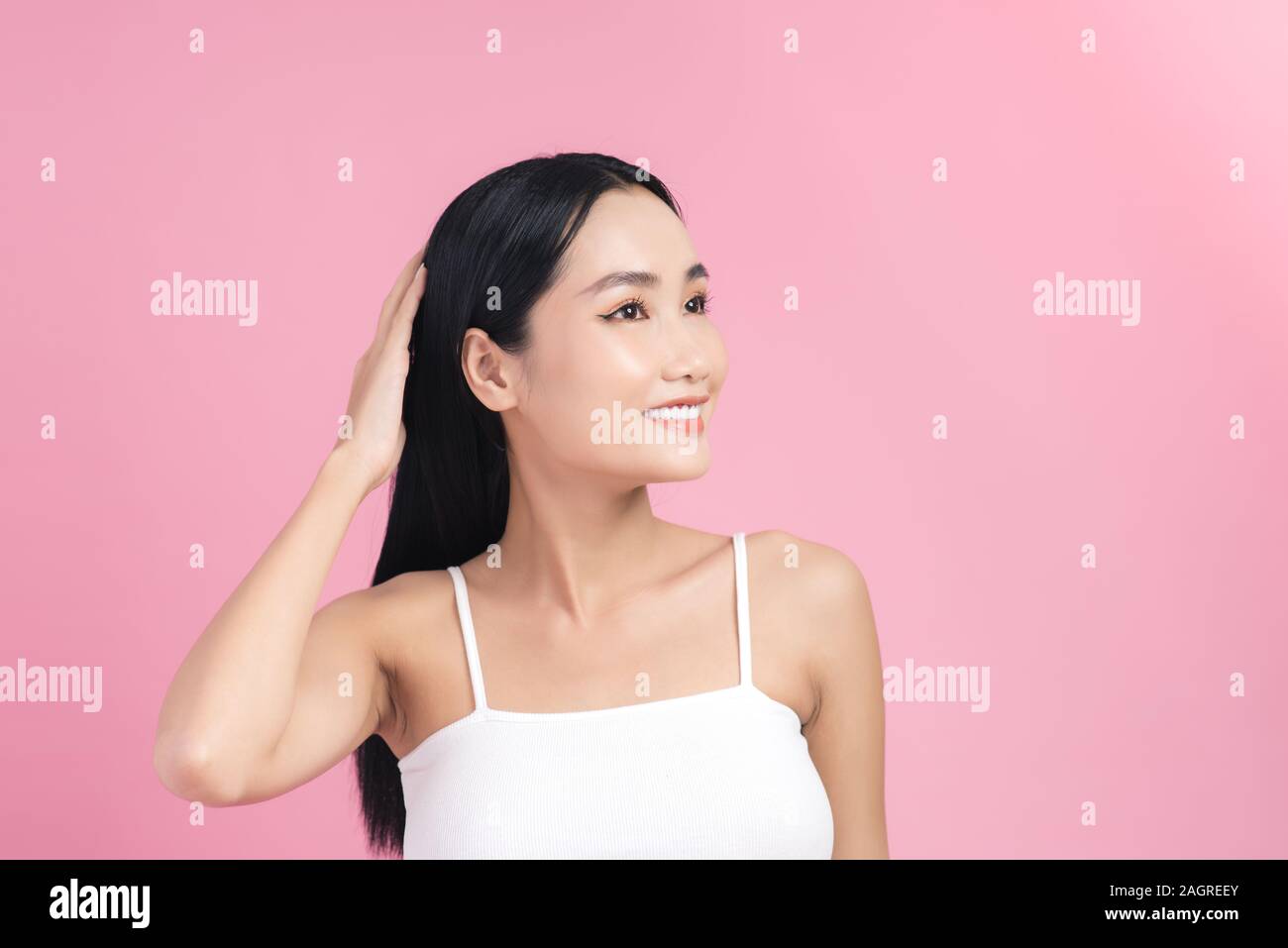 Giovane bella donna asiatica avendo cura dei suoi capelli. Ritratto di bellezza naturale , per il make-up, bellezza viso, isolate su sfondo rosa. Foto Stock