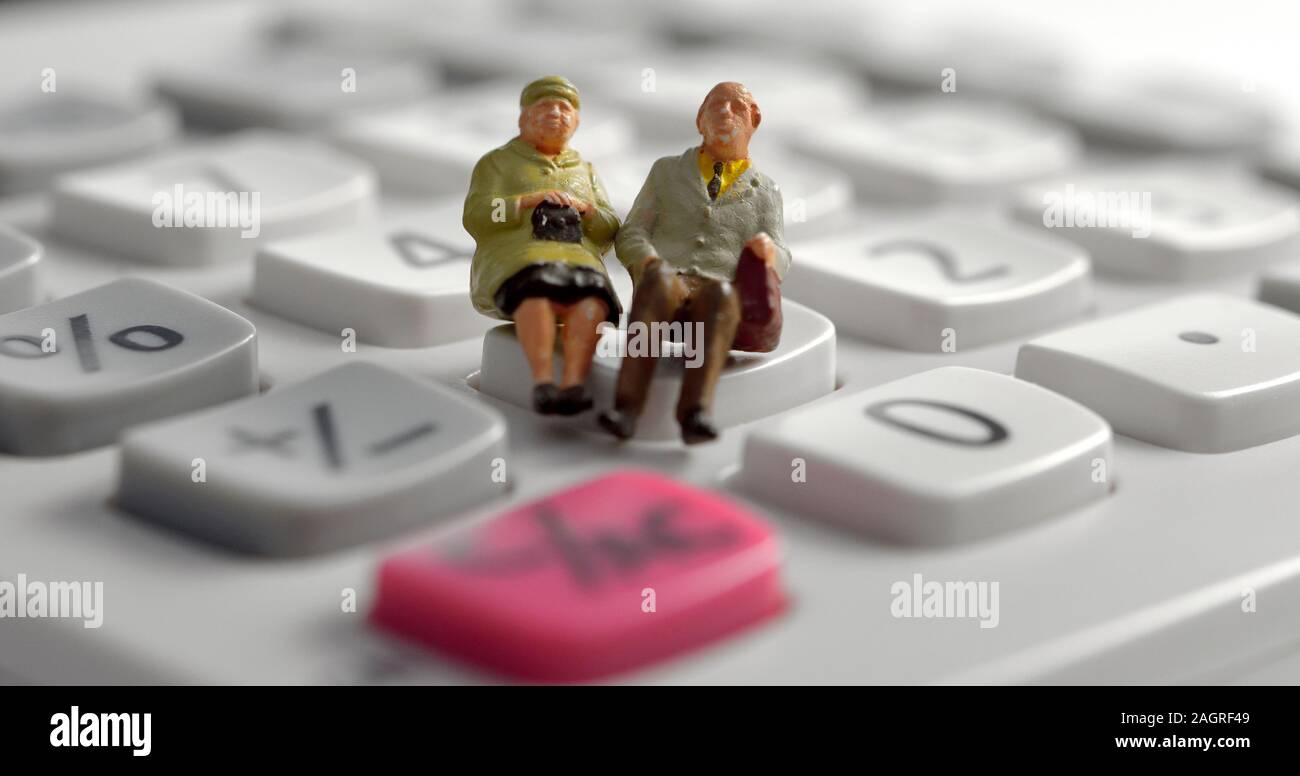 Titolare di pensione o di rendita in miniatura giovane seduto su di una calcolatrice Foto Stock