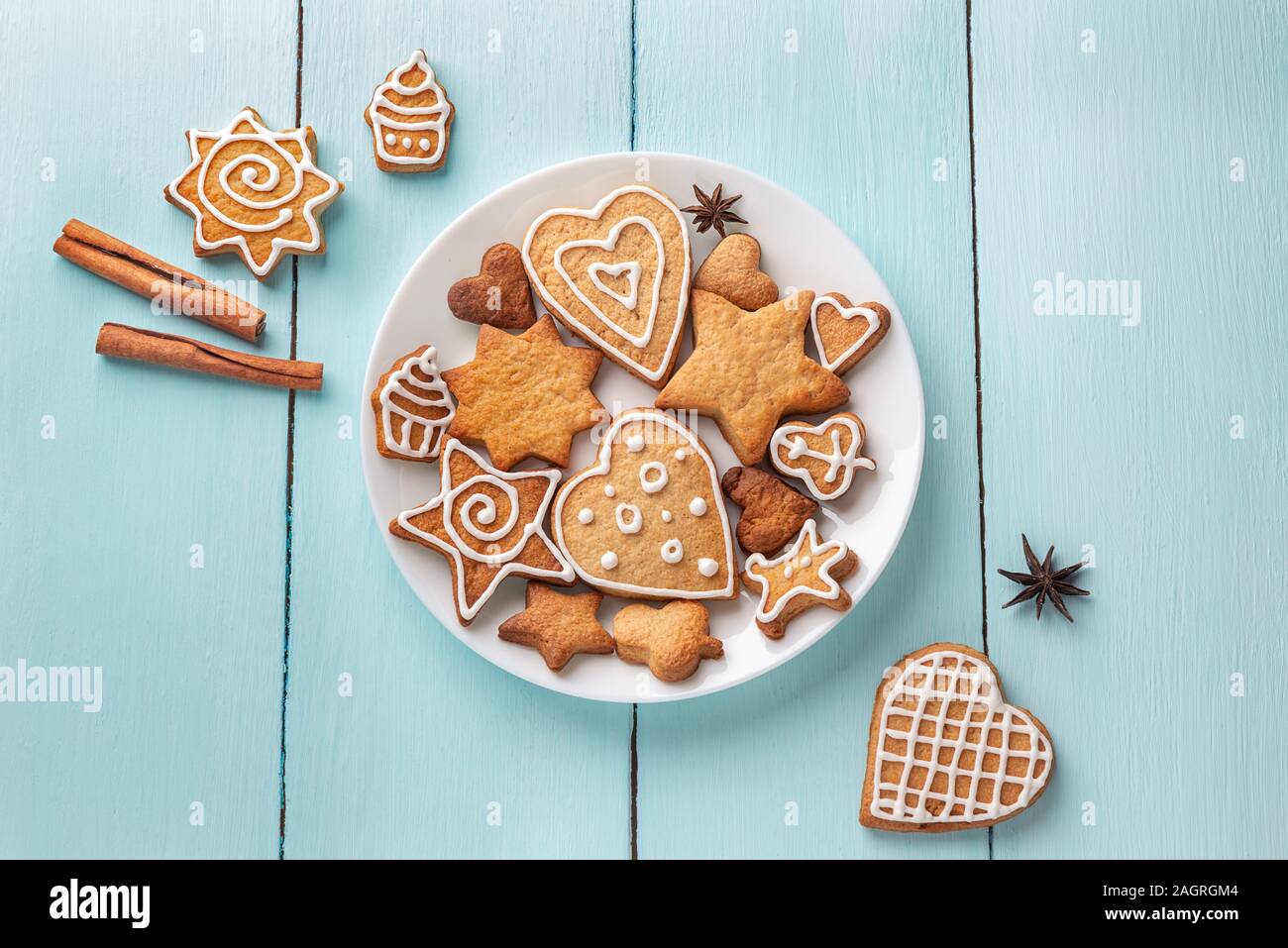 Biscotti allo zenzero decorate con la ciliegina su una piastra su un blu sullo sfondo di legno. Vista da sopra Foto Stock