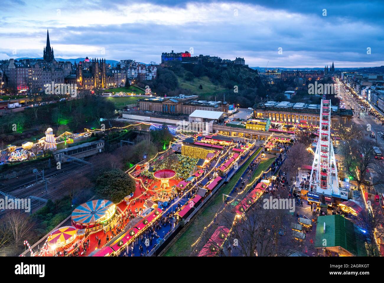 Vista di Edimburgo Il Mercatino di Natale a ovest di Princes Street Gardens e sullo skyline della città verso il castello di Edimburgo, Scozia, Regno Unito Foto Stock