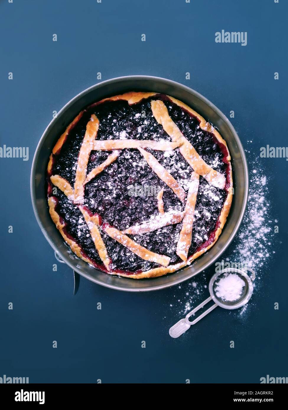 Torta rotonda con nero bacche Ribes su uno sfondo blu, una ricetta di pasta dolce da impasti Foto Stock