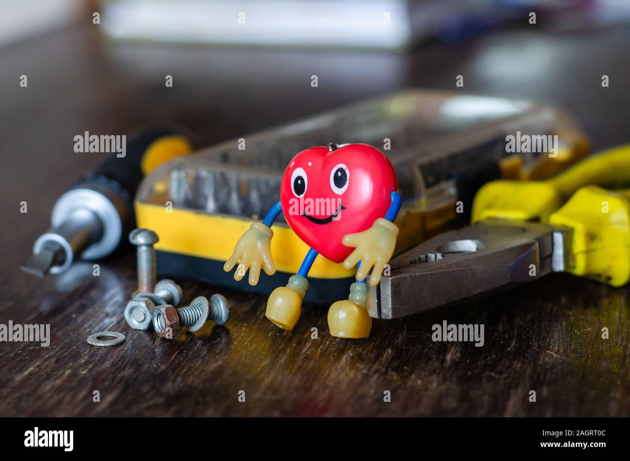 Utilizzate il Portachiavi a forma di cuore su un tavolo. Un bellissimo portachiavi accanto a un set di cacciaviti e un altro strumento mano.dono per la memoria e per fortuna Foto Stock