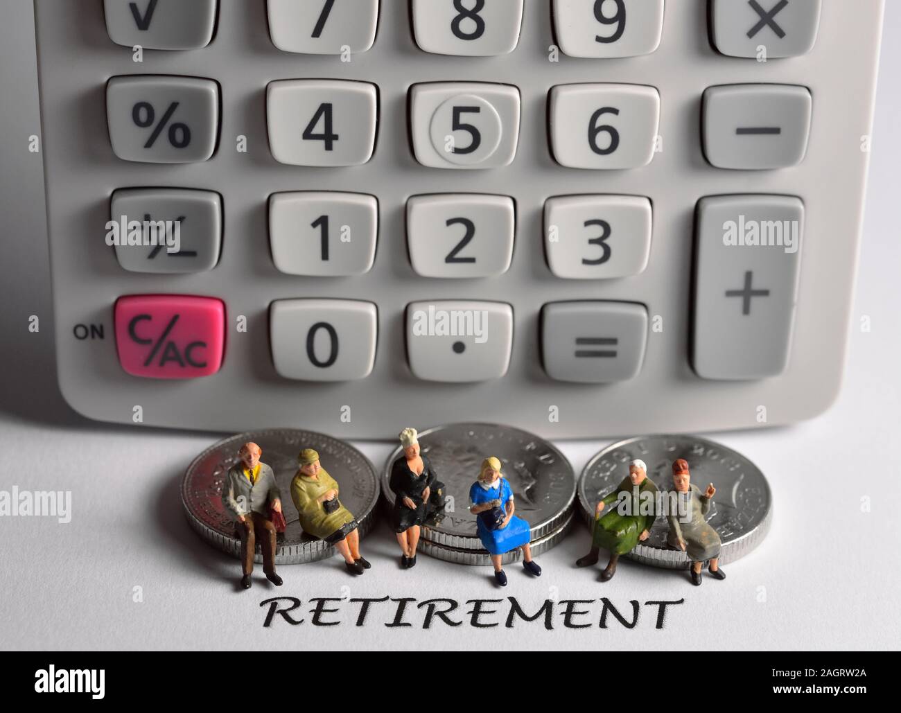 La gente seduta sulle monete dietro la parola pensionamento Foto Stock