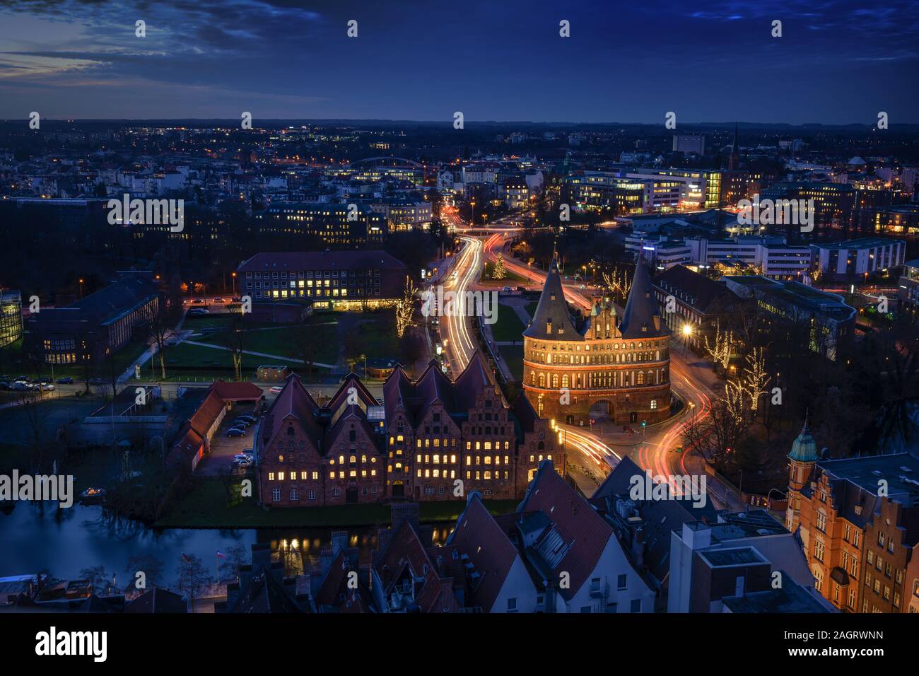 Antenna vista notturna della città illuminata di Lubecca, Germania in inverno con Holstentor e storiche case Salzspeicher, esposizione di lungo periodo a blue h Foto Stock