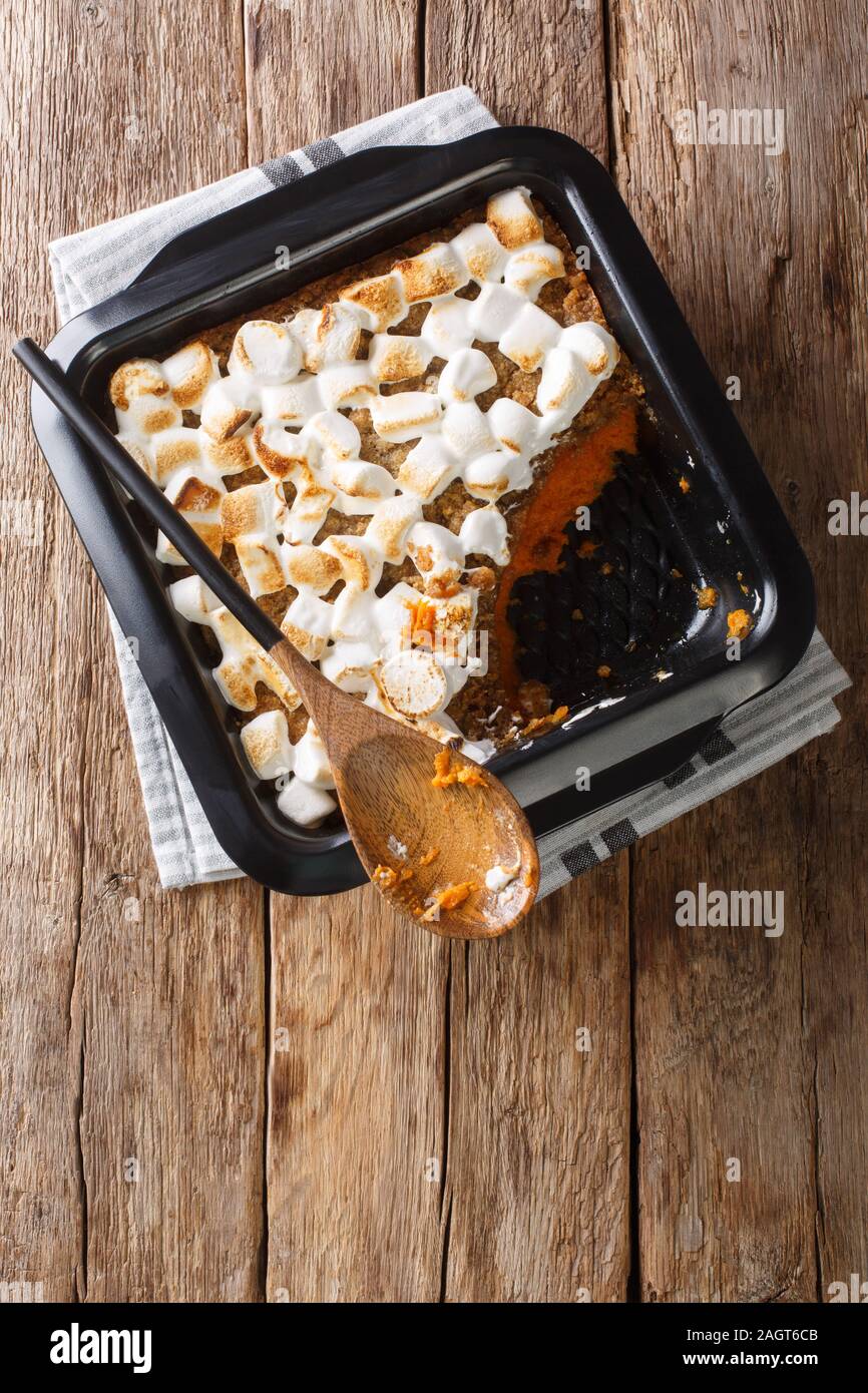 Festive patata dolce dolce con le noci pecan e marshmallows close-up in una teglia sul tavolo. Verticale in alto vista da sopra Foto Stock