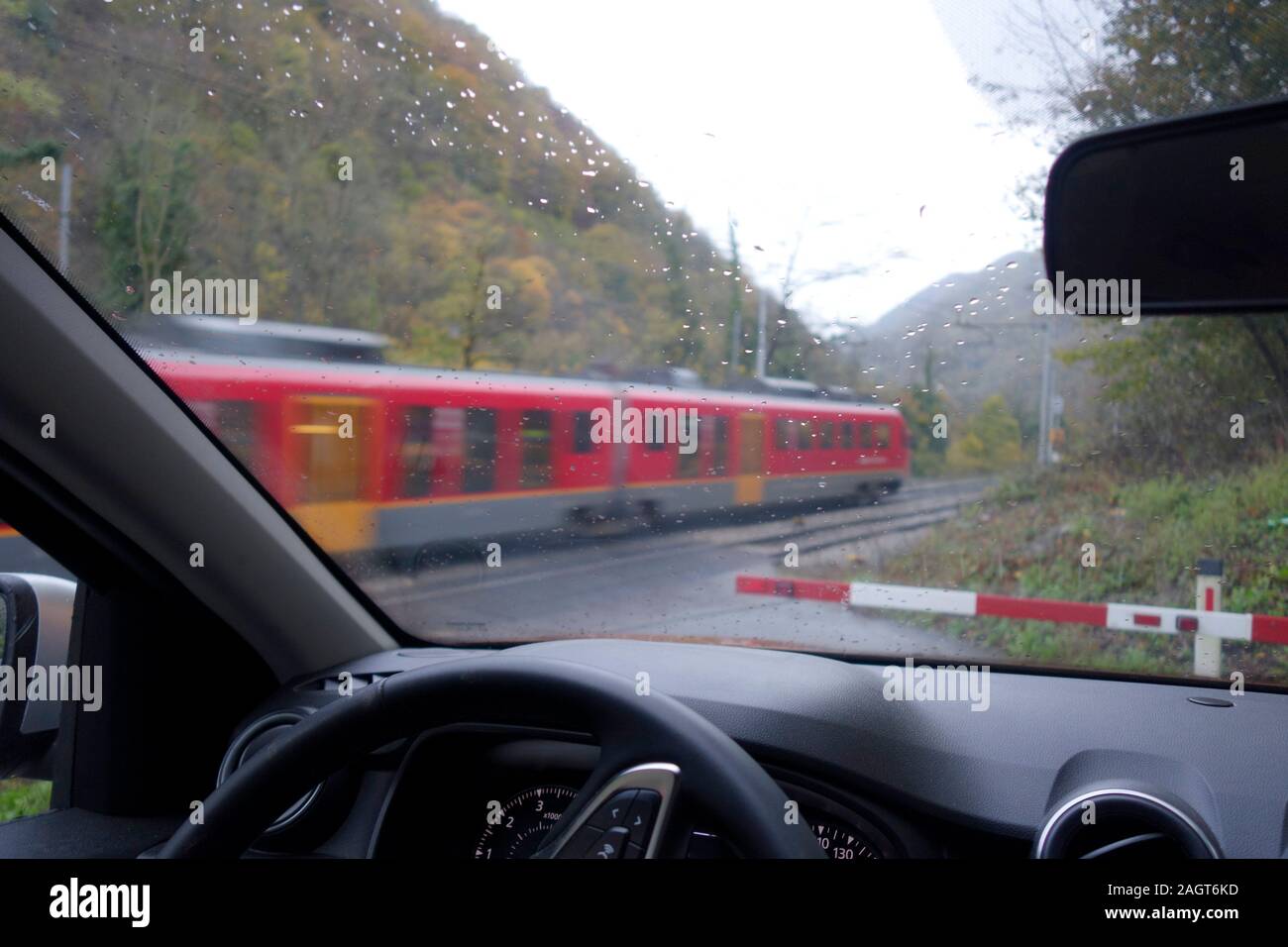Una vettura attende a livello ferroviario traversata per il treno che passa e attraversare il bar per il sollevamento. Foto Stock