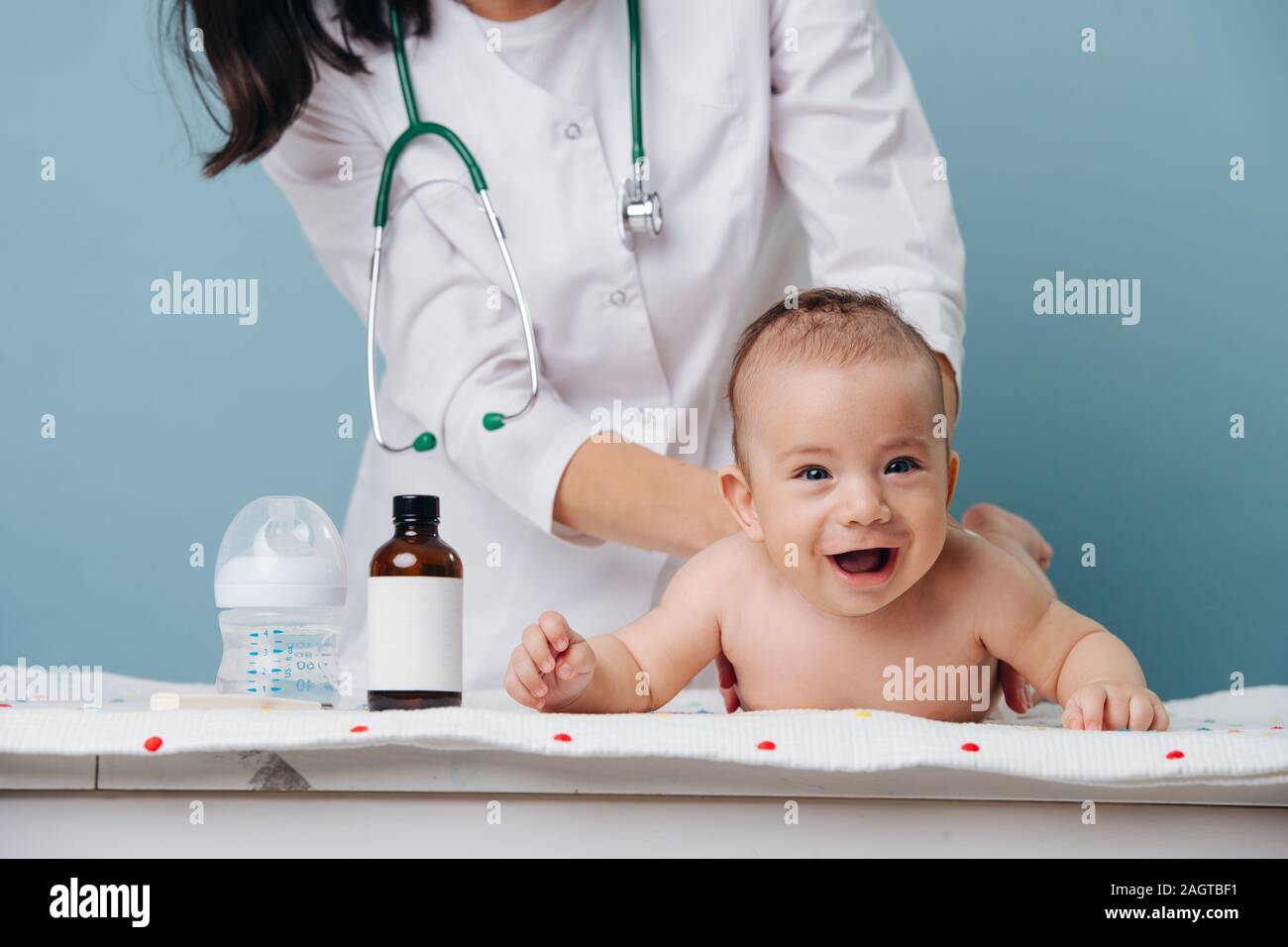 Little baby boy si trova su un tavolo sul suo stomaco a un appuntamento dal dottore Foto Stock