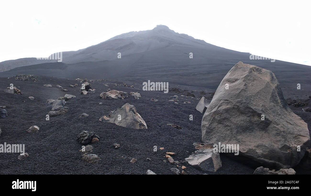 Un stark e desolata vulcano creater paesaggio con lava nera di sabbia e rocce e altri crateri dietro Foto Stock