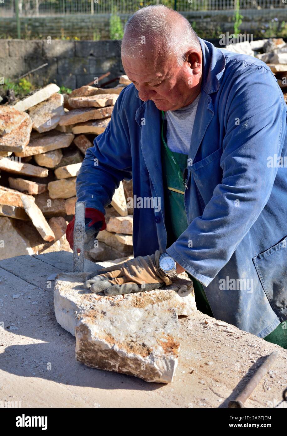 Artigiano la preparazione di pietra con un martello per asciugare la parete in pietra, Matohanci vicino a Pola, Croazia Foto Stock