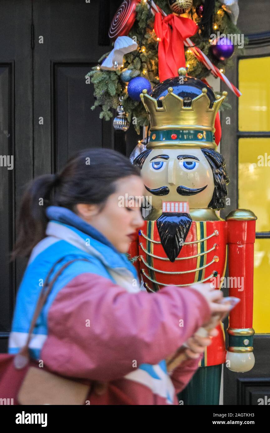 Central London, Londra, 21 dic 2019. Una donna cammina davanti a una grande in legno intagliato Rottura-nocciola in Argyll Street. Negozi, alberghi, ristoranti e residenze hanno tutte addobbate le sale decorate e i loro ingressi nella festosa splendore intorno a Mayfair e Oxford Street e Regent Street a Londra negli ultimi giorni prima di Natale. Foto Stock