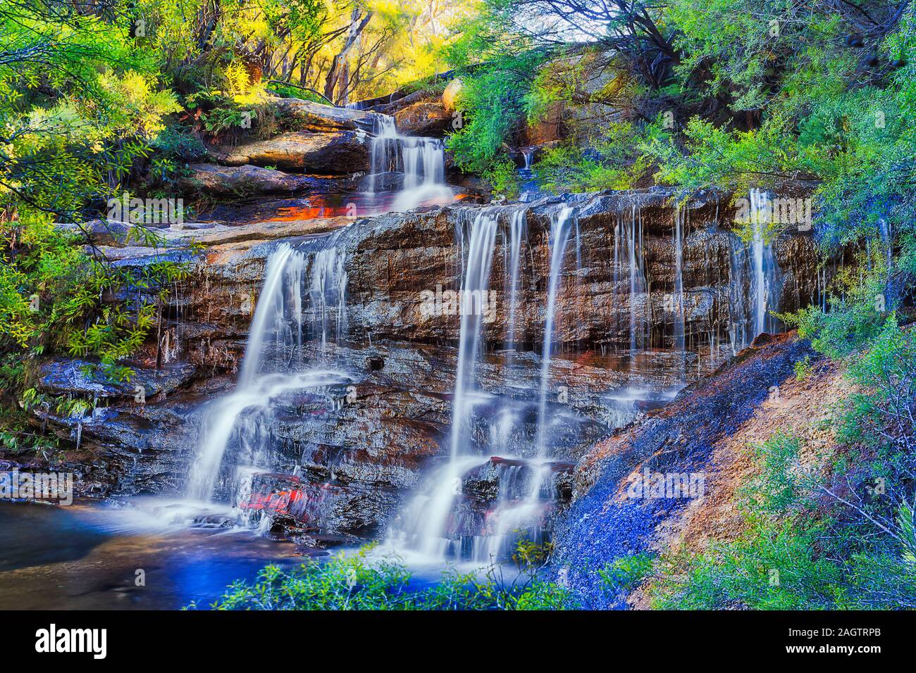 Cascata di cascate in Australian Blue Mountains taglio attraverso le rocce di arenaria nella evergreen gum tree forest sul soleggiato al mattino invernale. Foto Stock