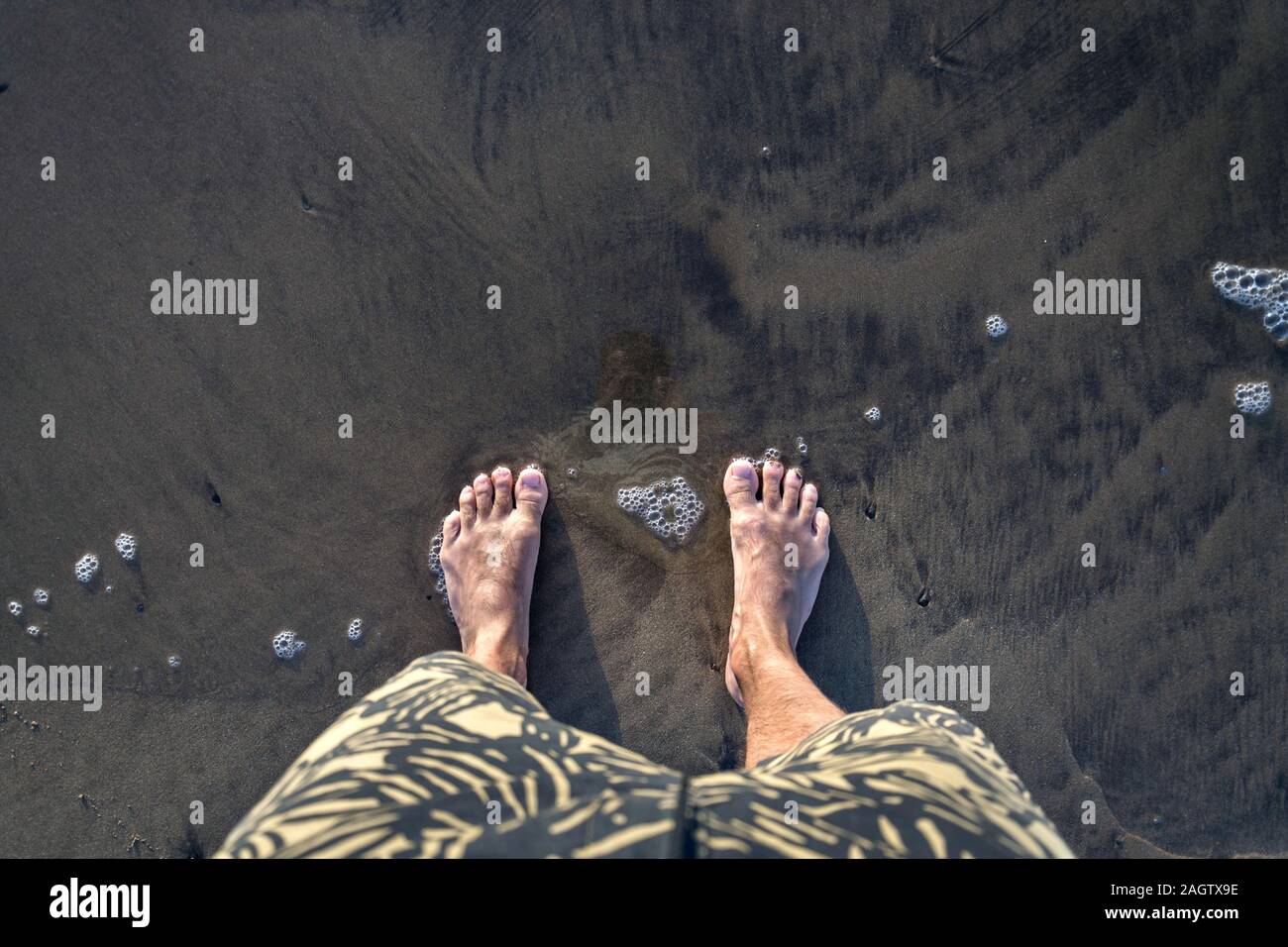 Umano piedi scalzi nella sabbia bagnata sulla riva del mare, attiva una vita sana e di crescita personale concetto di spazio di copia Foto Stock
