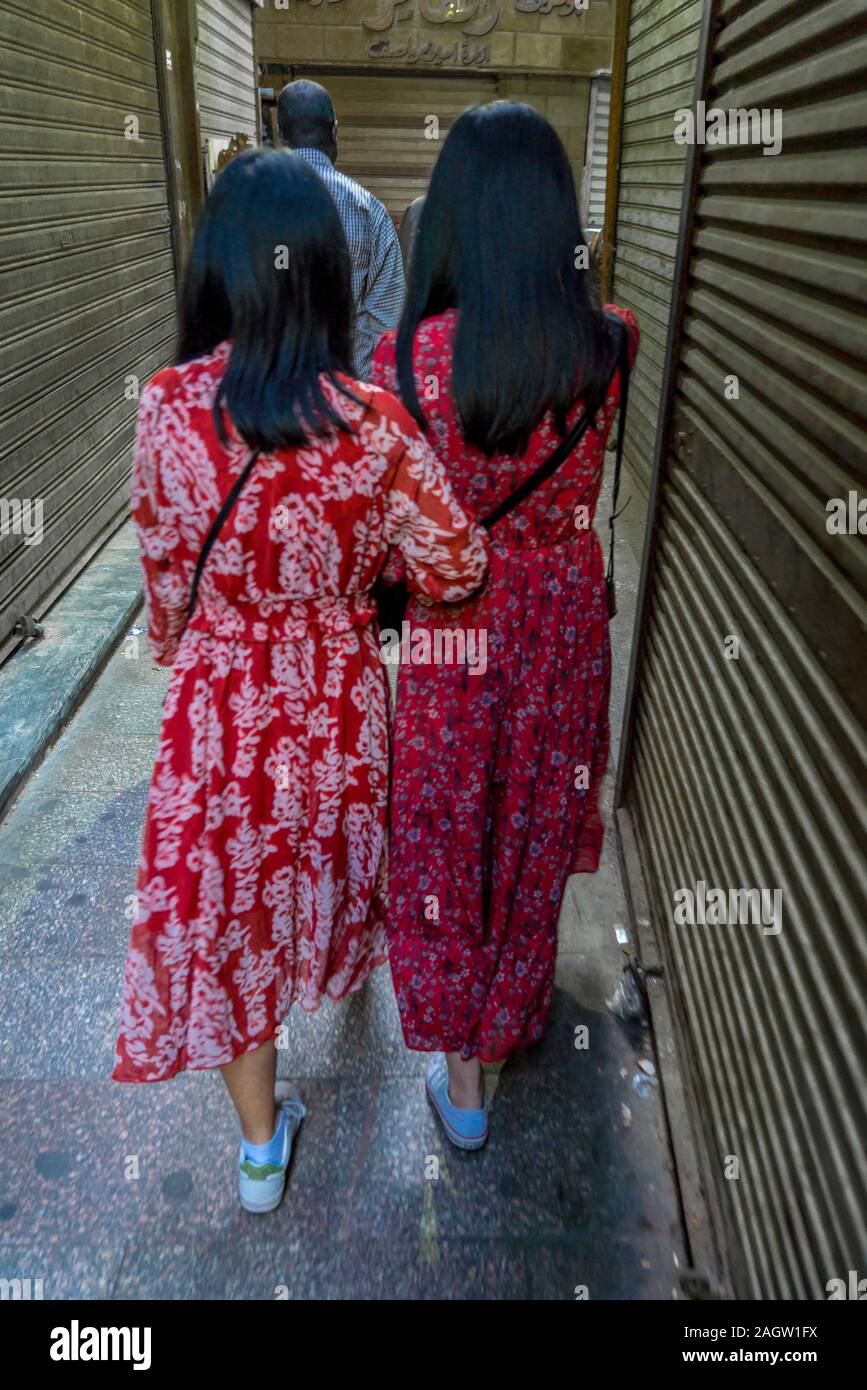 Novembre 2019, Luxor, Egitto - popolo musulmano di Egitto fare shopping a Luxor Souq - due donne usura luminoso rosso abiti da dietro Foto Stock