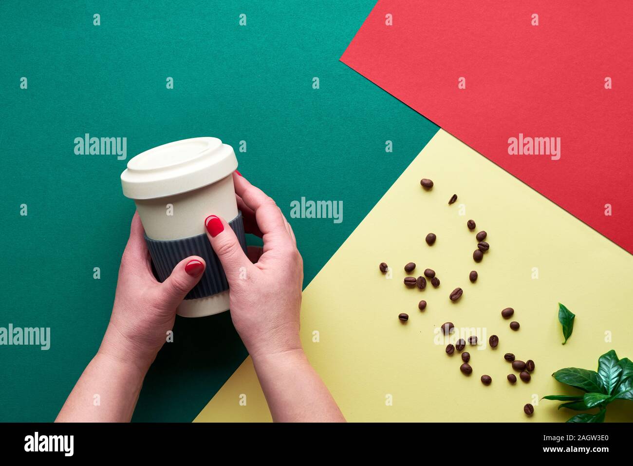 Rifiuti Zero il concetto di caffè. Eco Friendly riutilizzabili tazze di caffè in mani. Piano geometrico giaceva sul dividere in due toni di carta. Background creativo in verde scuro, Foto Stock