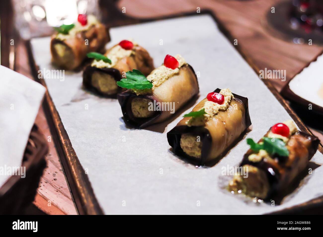 Georgian National melanzane fritte panini farciti con noci tritate e spezie con i semi di melograno su un tavolo di legno. Foto Stock